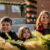 Three children smile in a Christmas decorated park