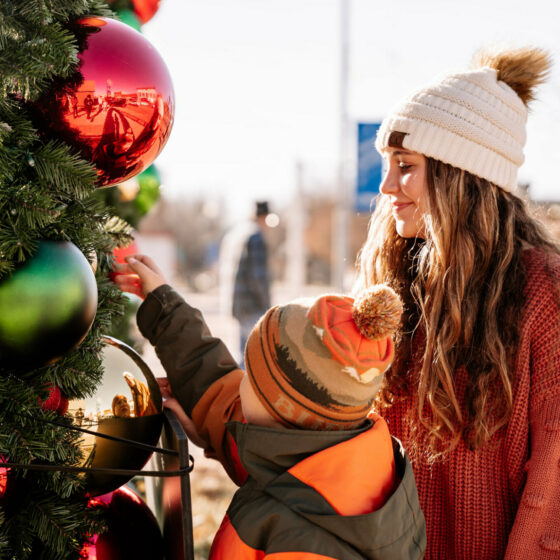 A young boy shows his sister a Christmas Tree bulb