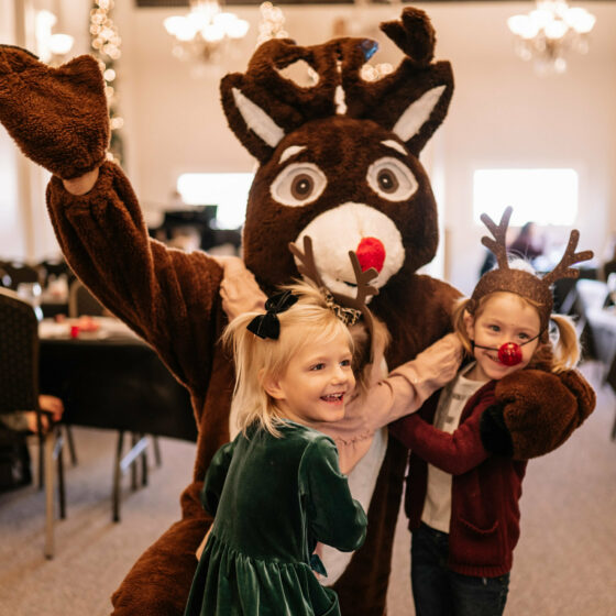 Two little girls hug rudolph