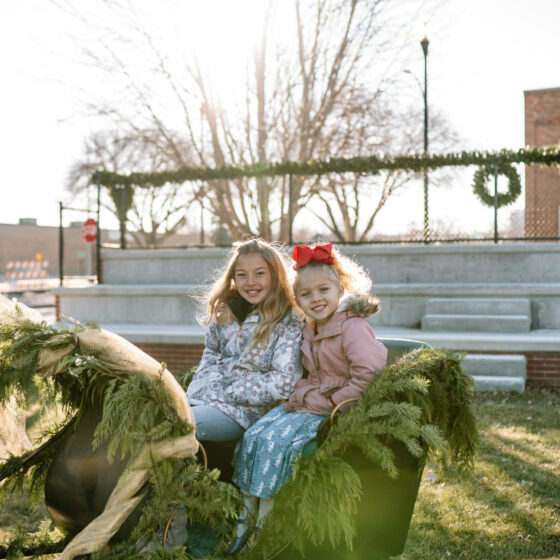 Two young sisters smile sitting inside a sleigh